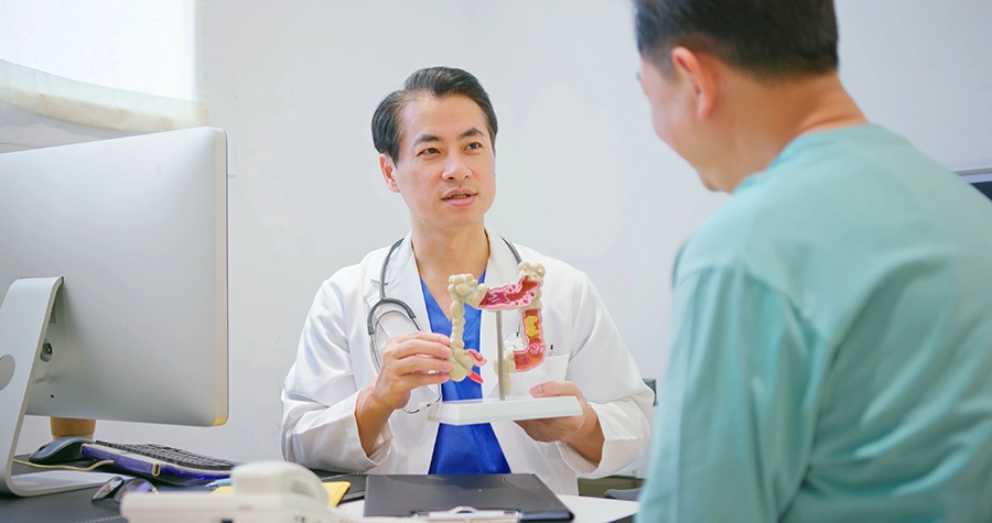 Doctor explaining a colon anatomy model to a patient during a consultation in a medical office